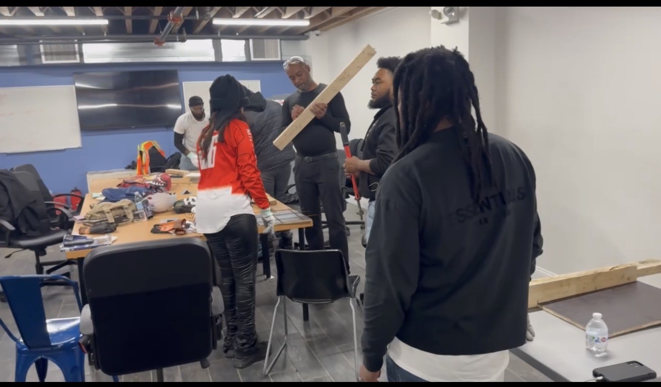Trainees learning construction fundamentals around a workshop table