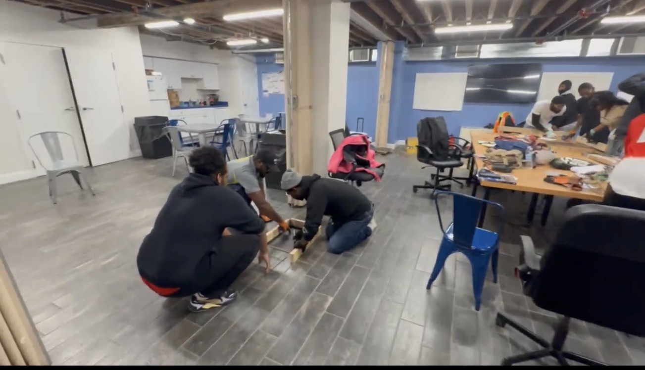Trainees practicing measuring and framing skills on a workshop floor