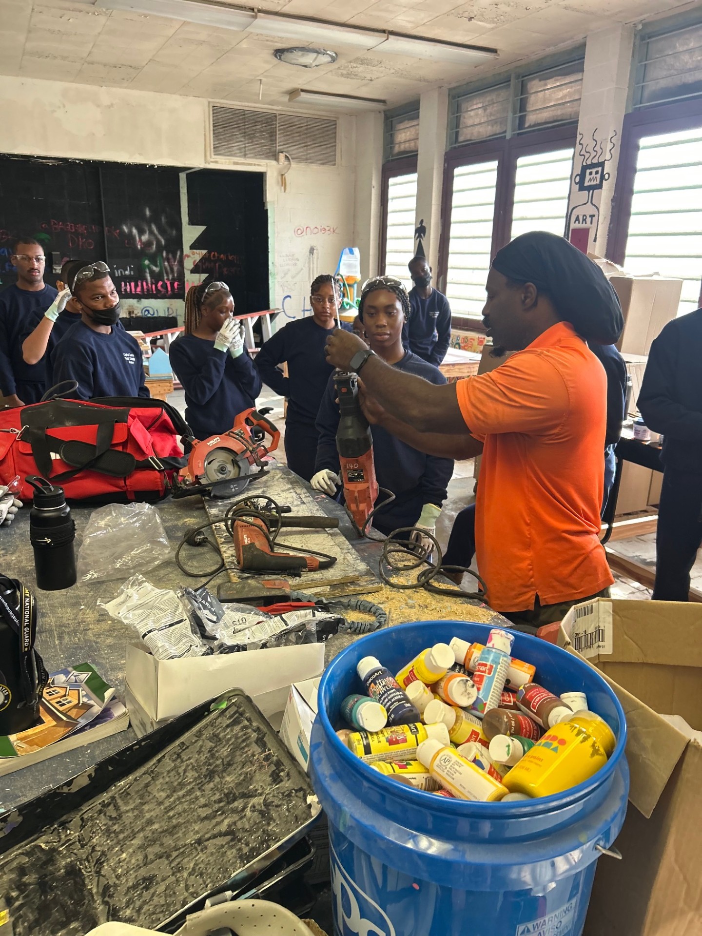Instructor demonstrating power tool safety to a group of trainees