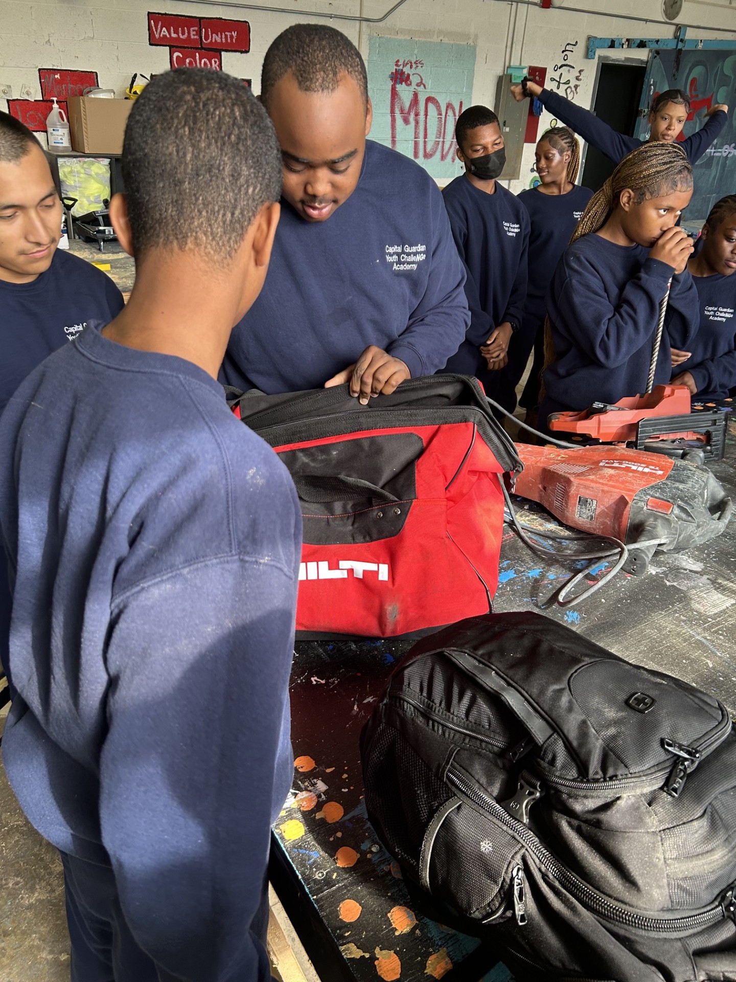 Trainees gathered around tools and equipment during workshop orientation